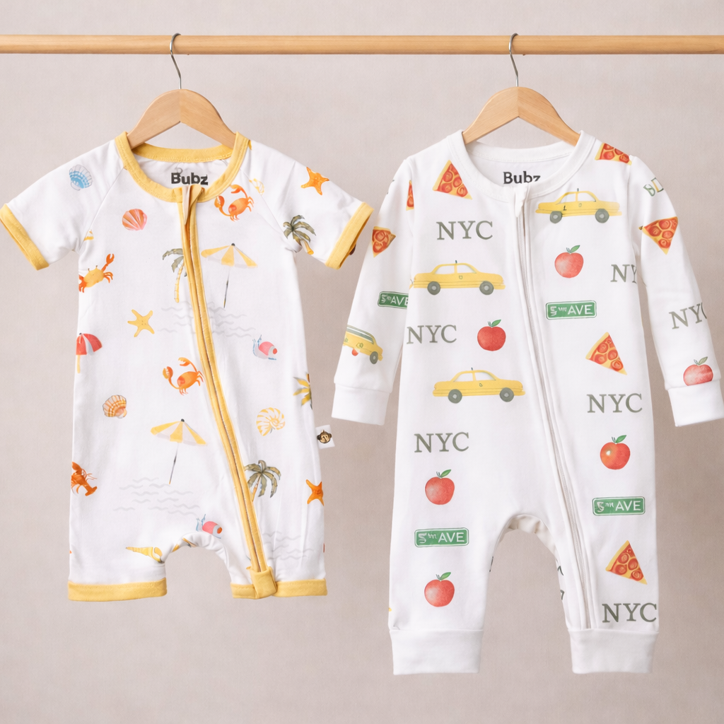 Two baby rompers with colorful prints on hangers against a neutral background