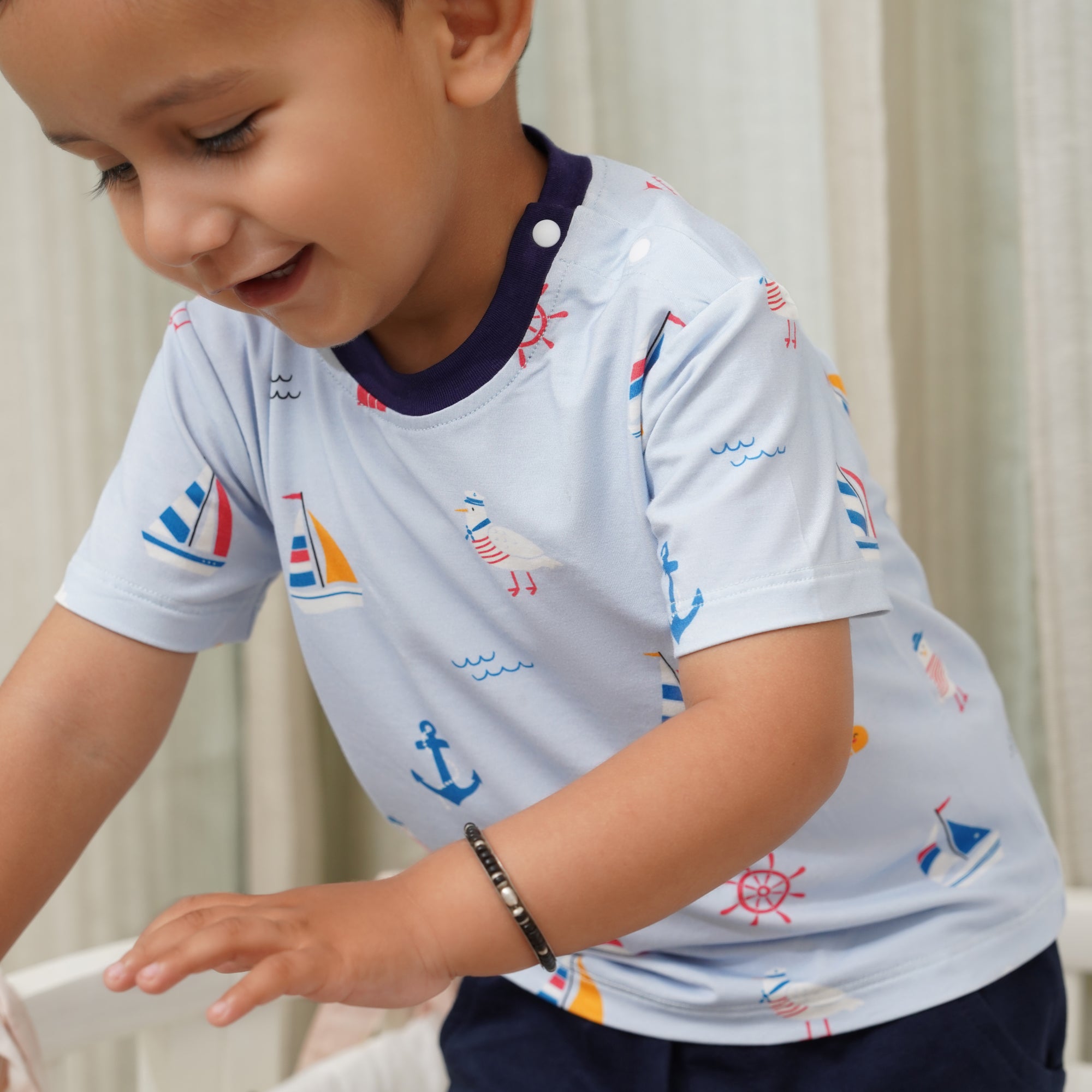 Child wearing a light blue bamboo shirt with nautical patterns on a neutral background