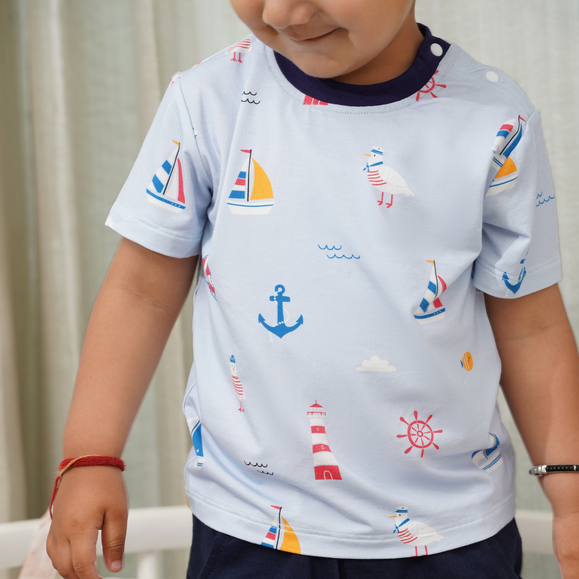 Child wearing a light blue bamboo shirt with nautical patterns against a neutral background