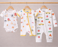 Three baby rompers with various prints on hangers against a plain background