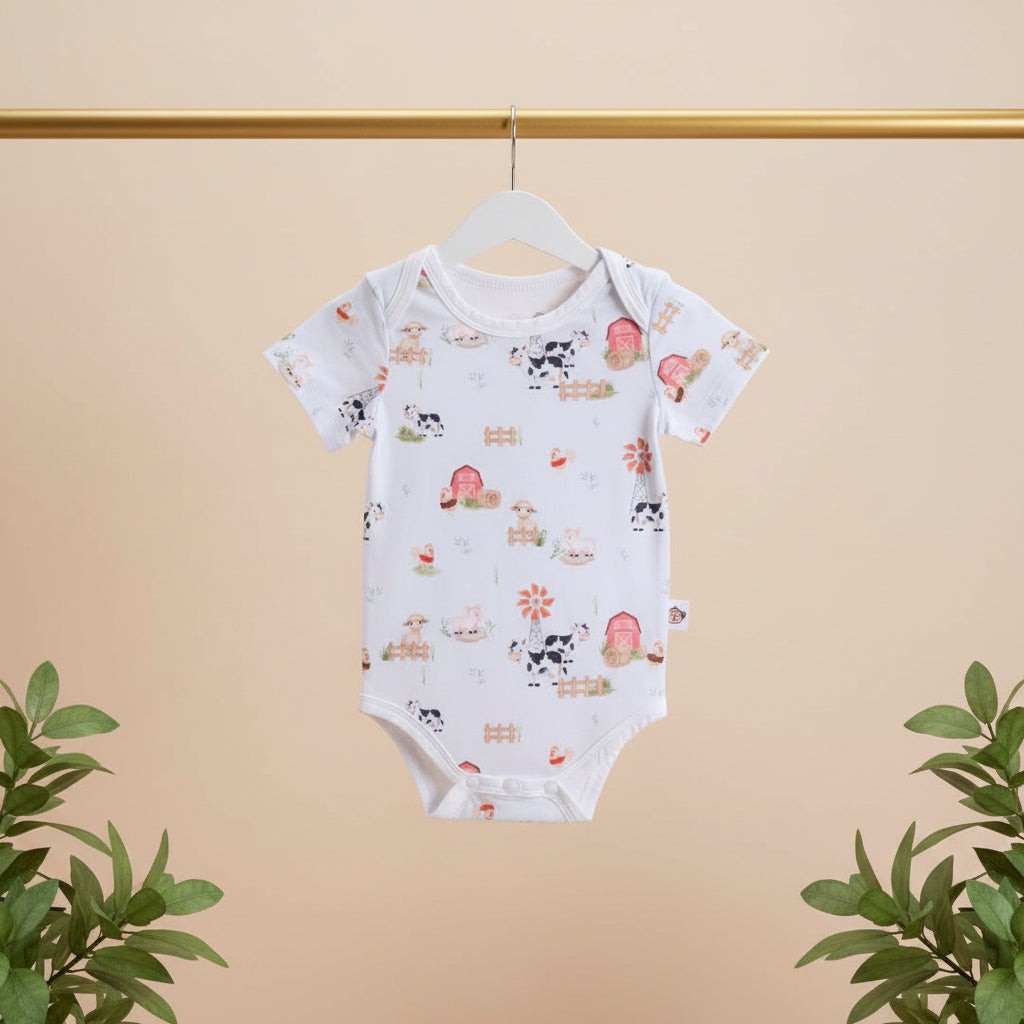 Baby onesie with farm animal pattern on a hanger against a beige background