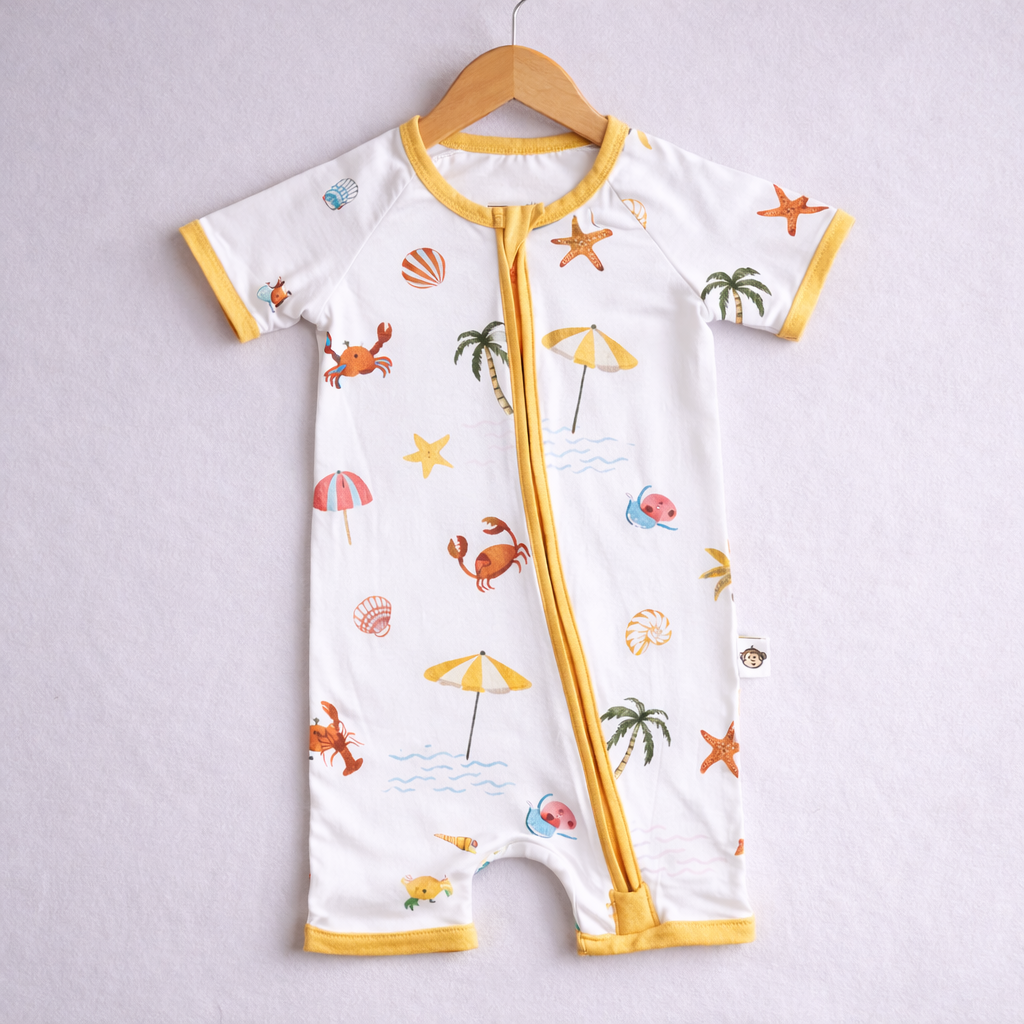 Baby romper with beach-themed print on a hanger against a light gray background