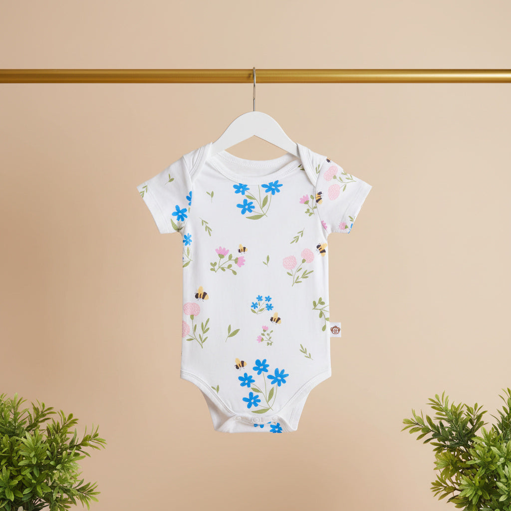 Baby onesie with floral pattern on a hanger against a beige background