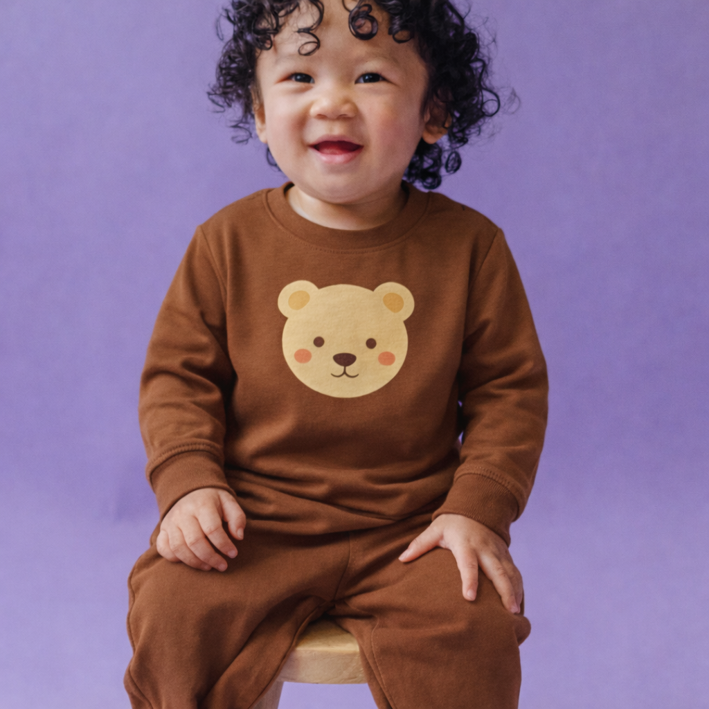 Child wearing a brown outfit with a bear face design against a purple background