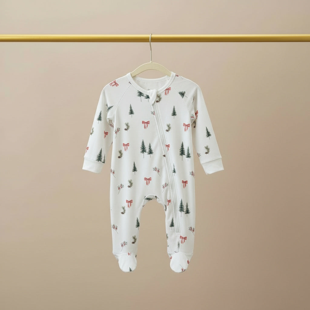 Baby onesie with forest pattern on a hanger against a beige background