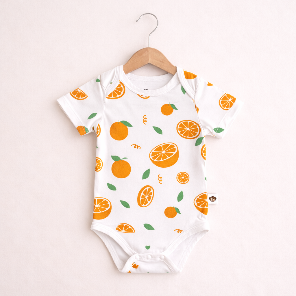 Baby onesie with orange pattern on a hanger against a light background