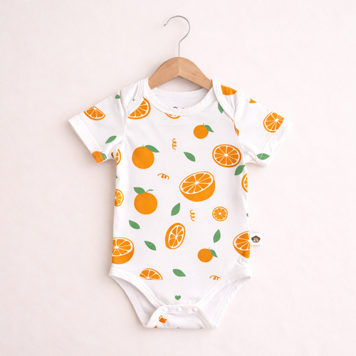 Baby onesie with orange pattern on a hanger against a light background