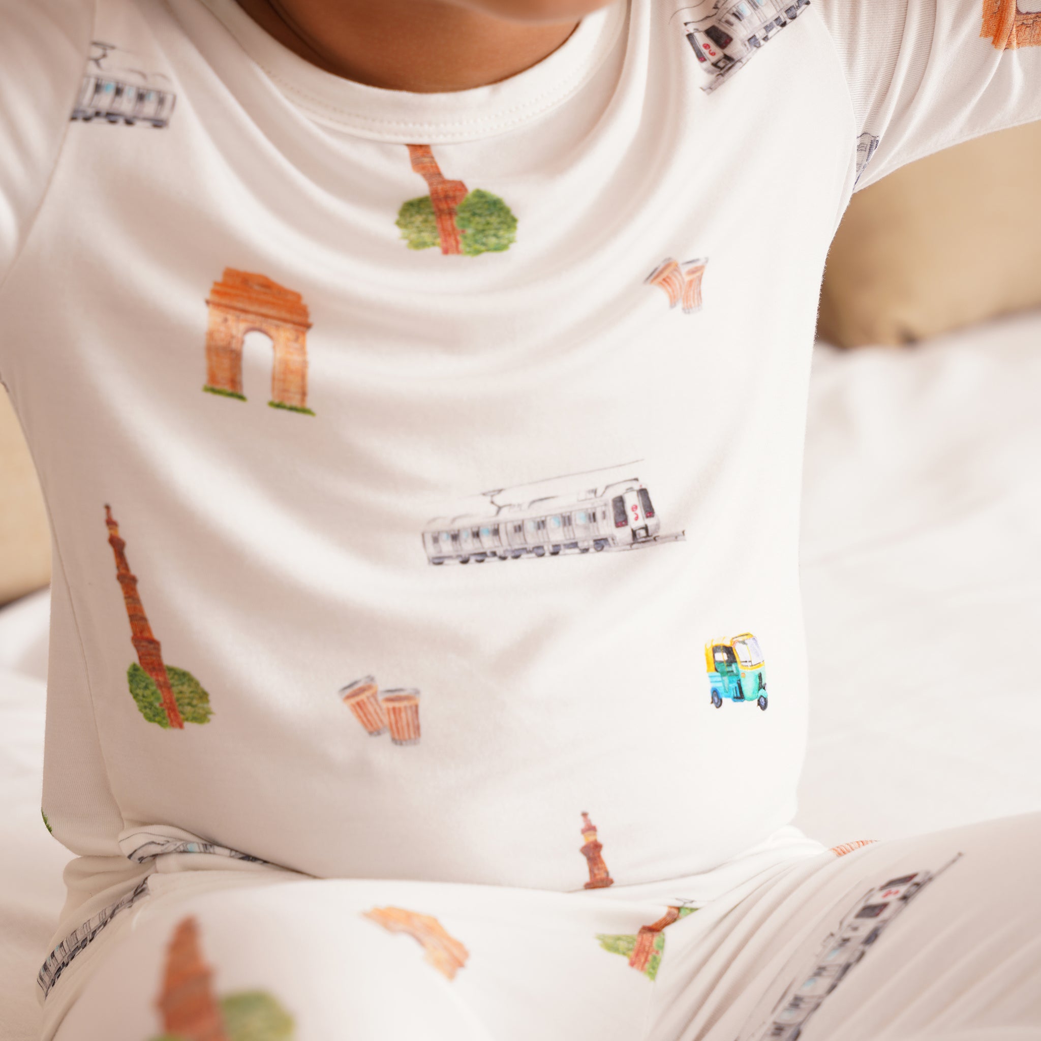 Child wearing a white bamboo shirt with colorful illustrations of landmarks and vehicles.