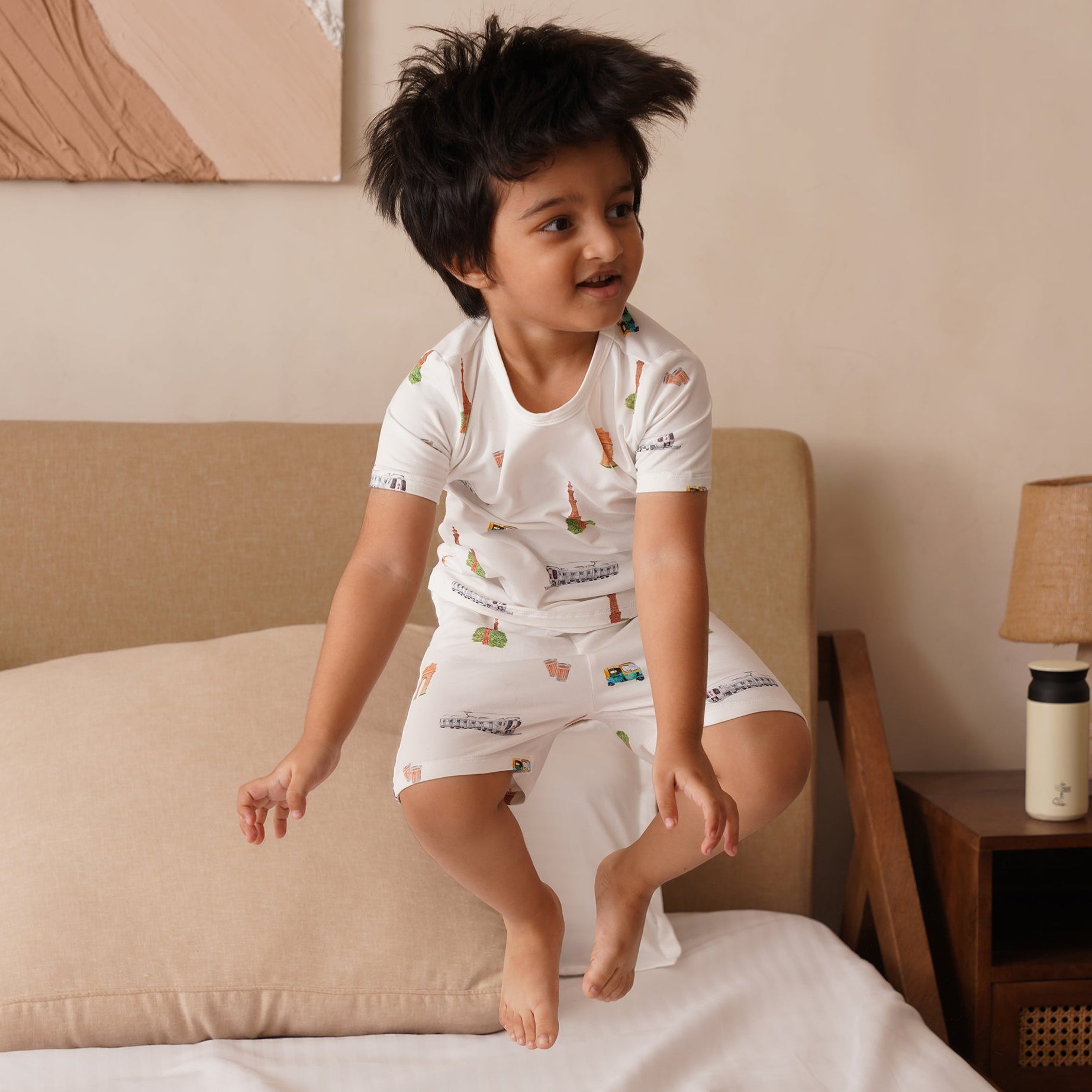 Child in bamboo pajamas sitting on a bed in a bedroom setting
