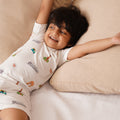 Child wearing a white bamboo shirt with colorful patterns, lying on a beige couch.