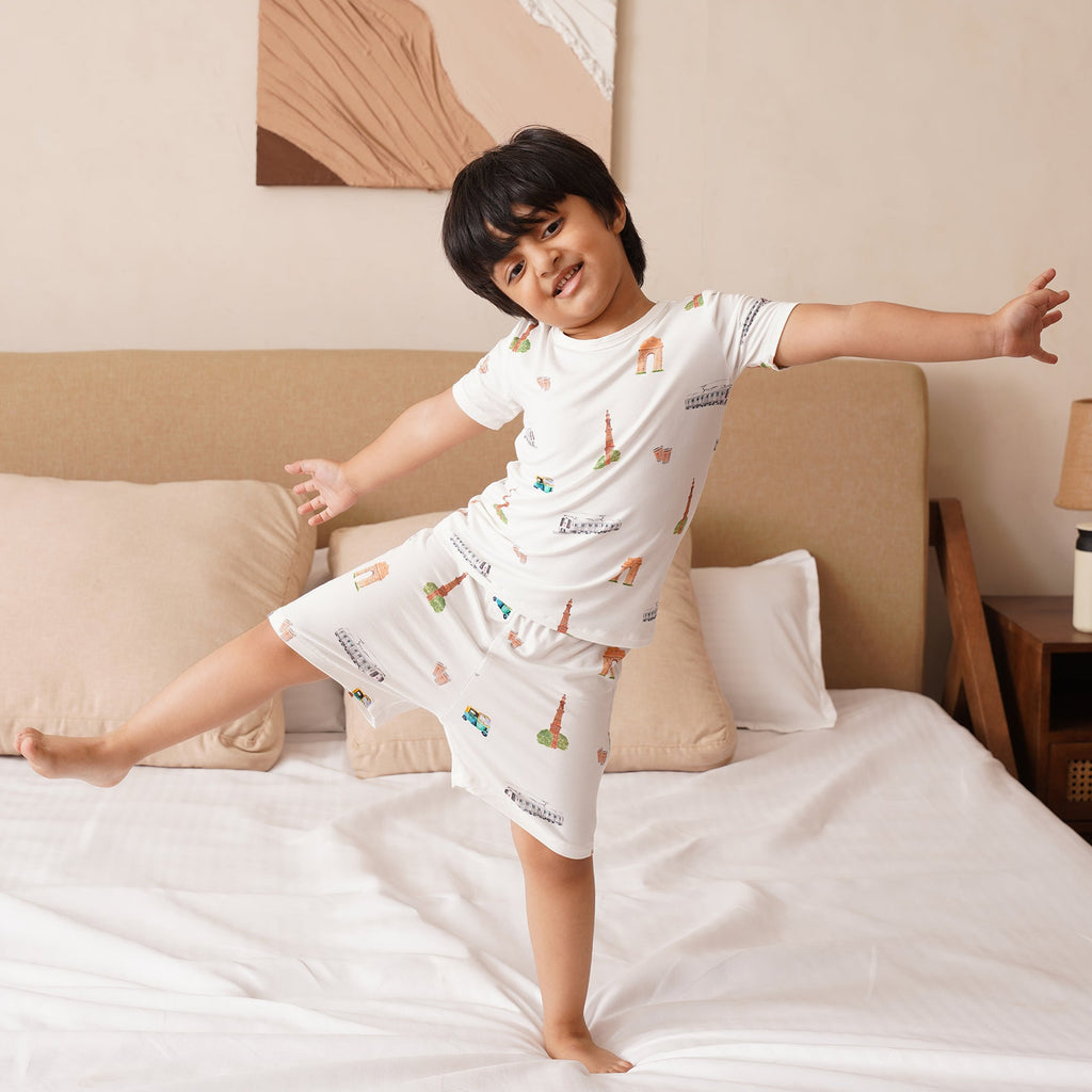 Child in bamboo pajamas jumping on a bed in a bedroom