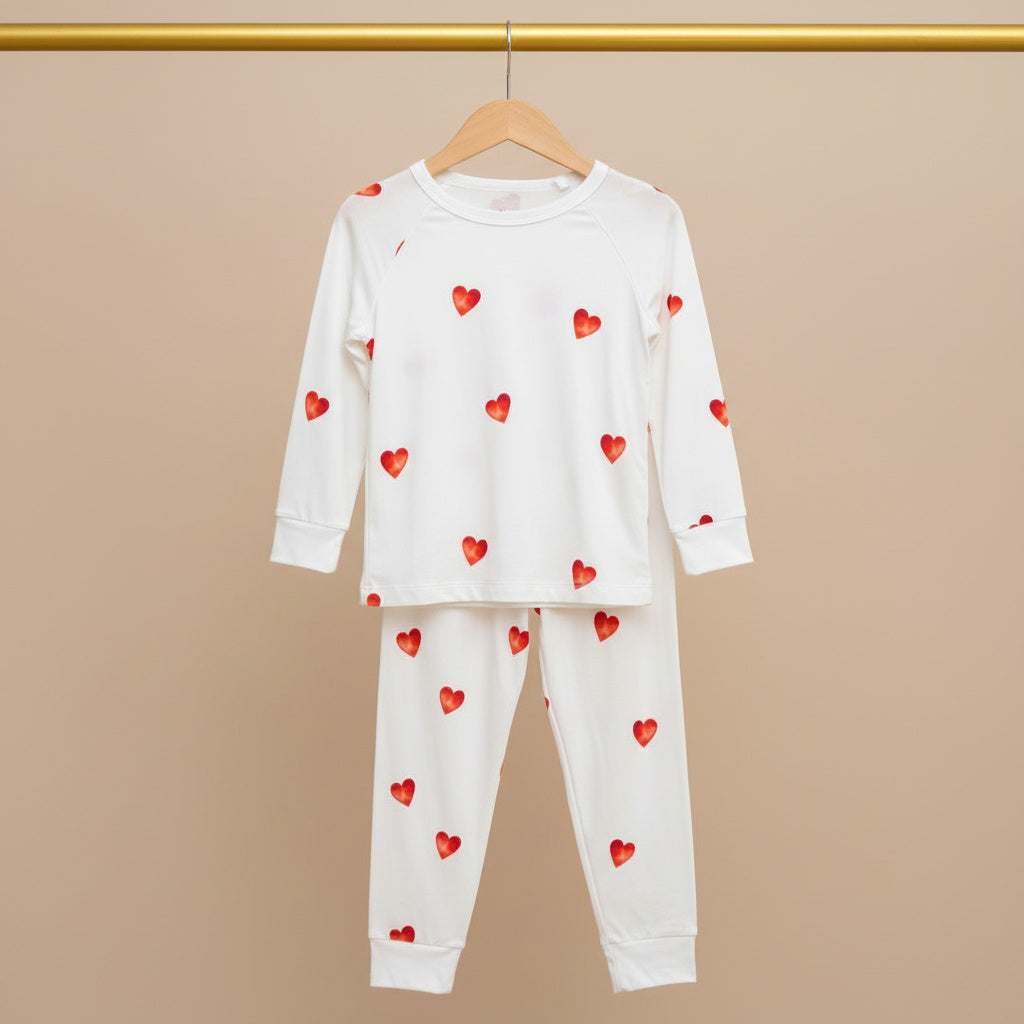 Children's pajama set with red heart patterns on a beige background