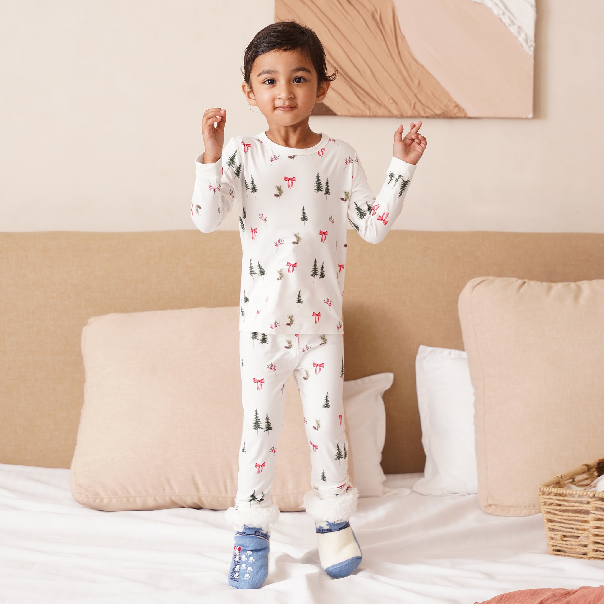 Child wearing a bamboo white pajama set with animal prints in a bedroom setting.