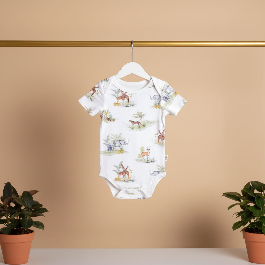 Baby onesie with animal pattern on a hanger against a beige wall with two potted plants.