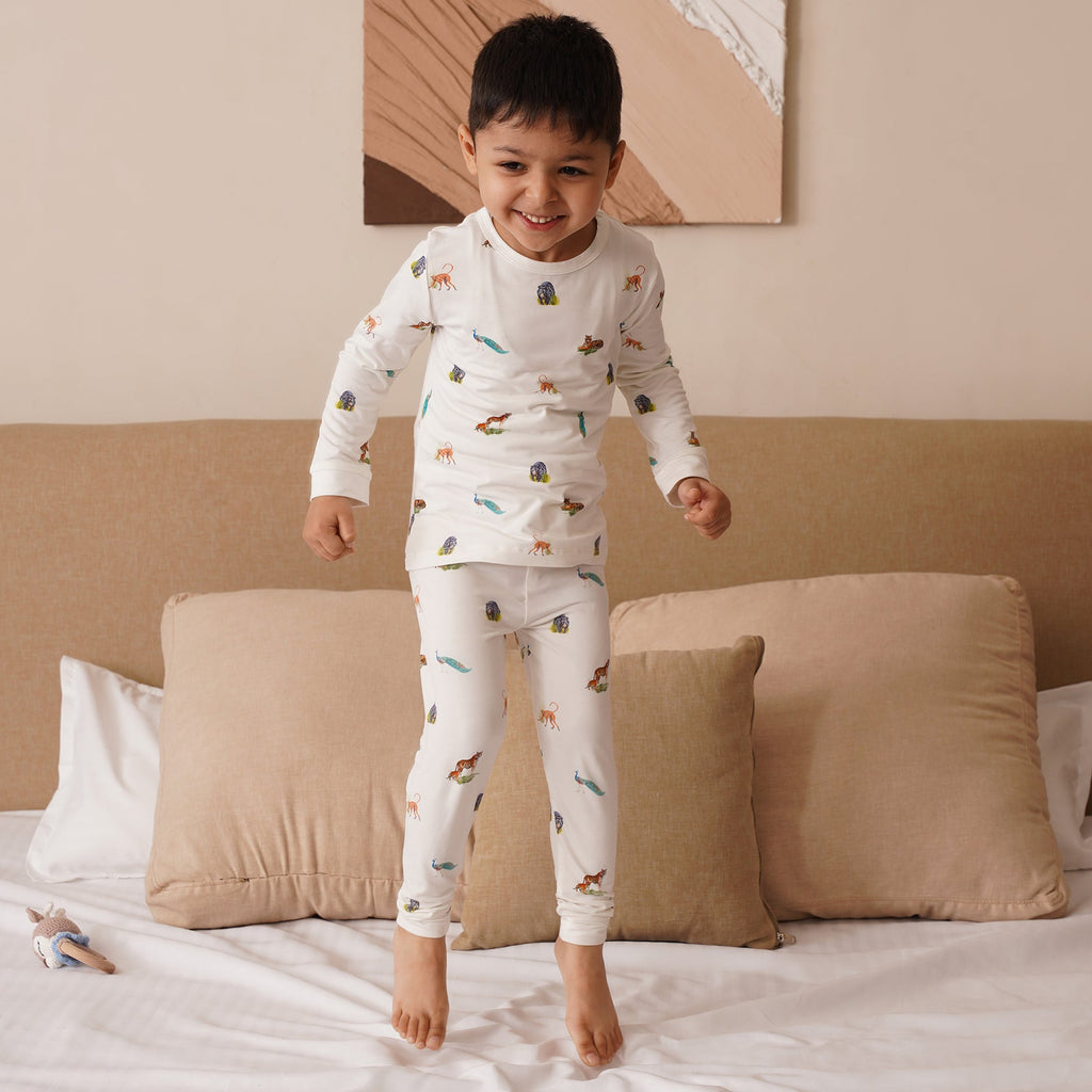 Child in bamboo pajamas standing on a bed in a bedroom