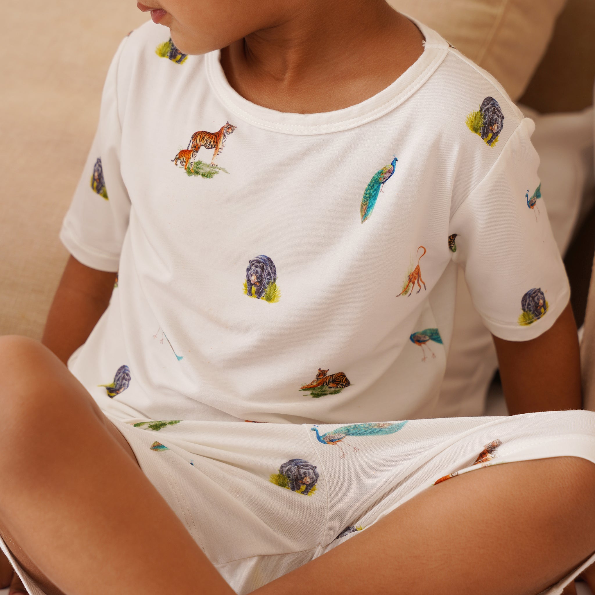 Toddler wearing a white bamboo pajama set with animal prints.