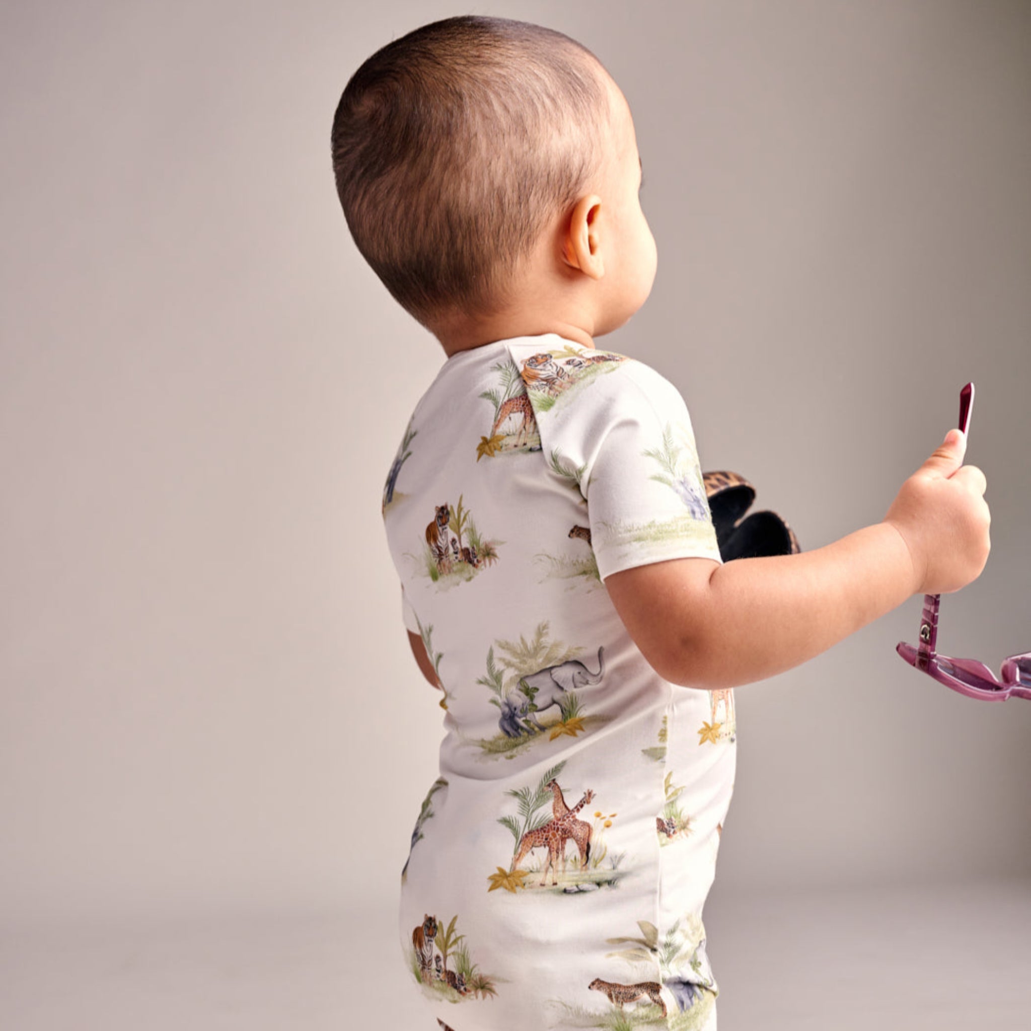 Child wearing a white outfit with animal prints on a plain background