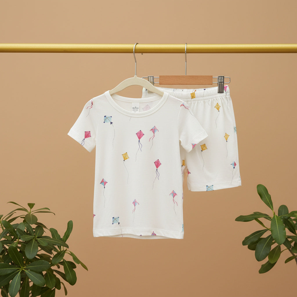 Children's pajama set with kite pattern on a hanger against a beige background