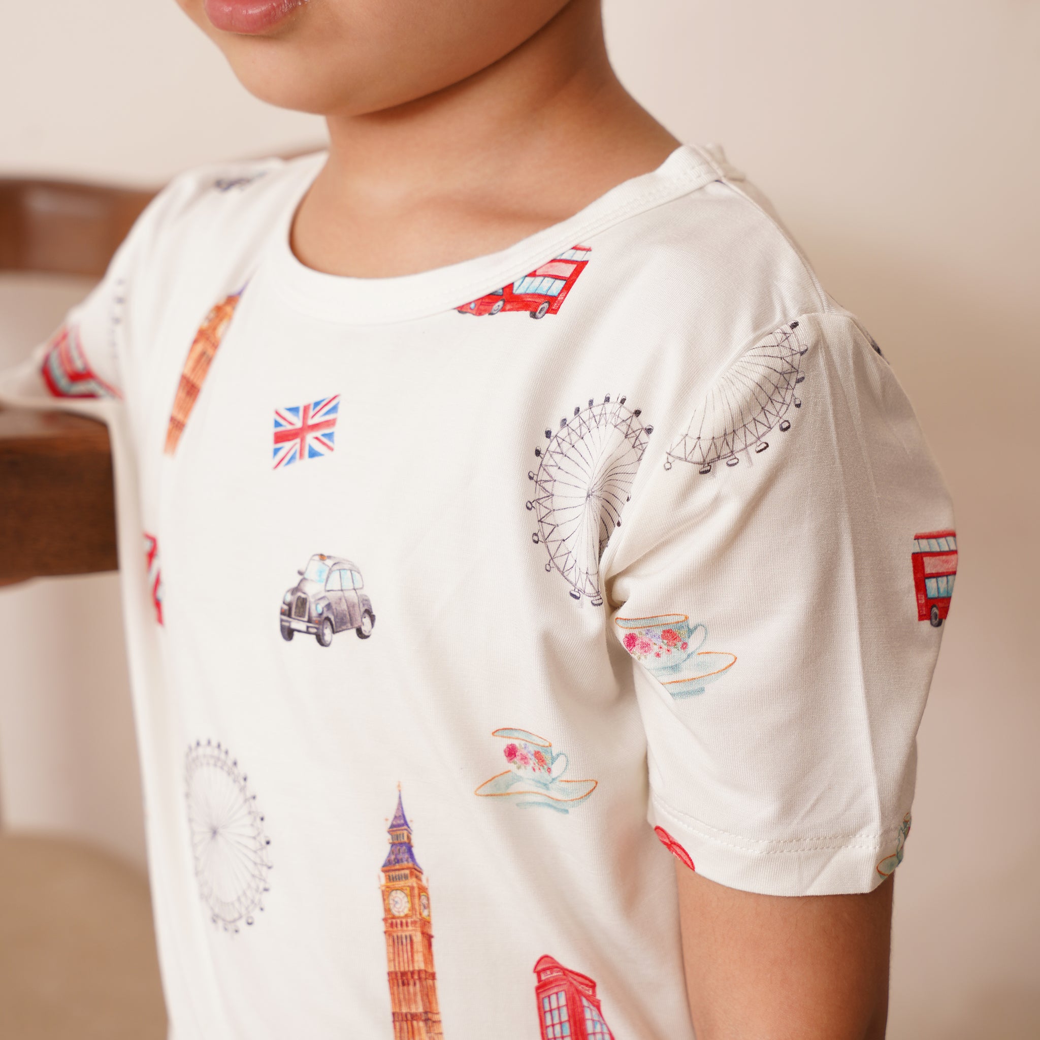 Child wearing a white bamboo t-shirt with British-themed designs.