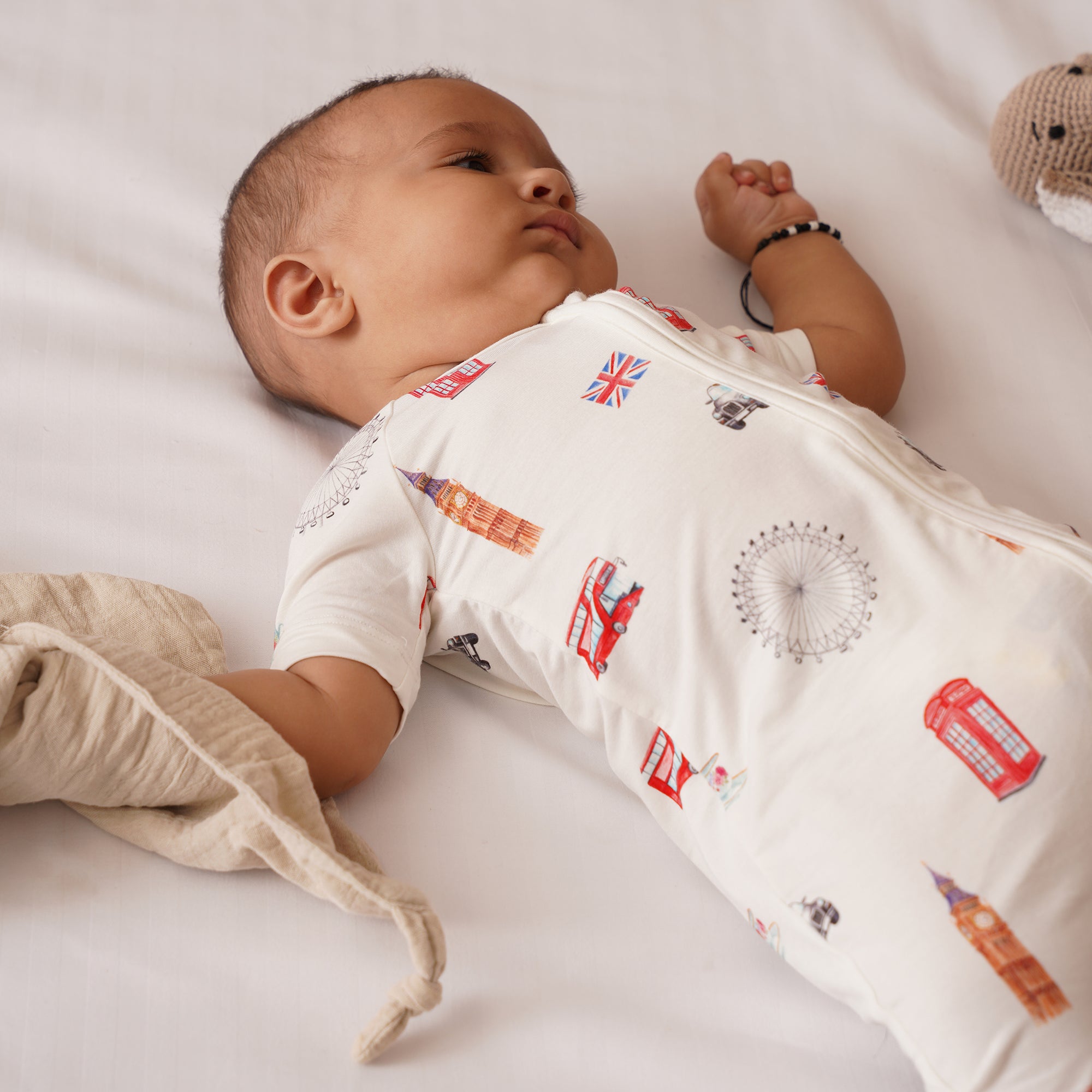 Baby wearing a white bamboo onesie with colorful patterns on a white background