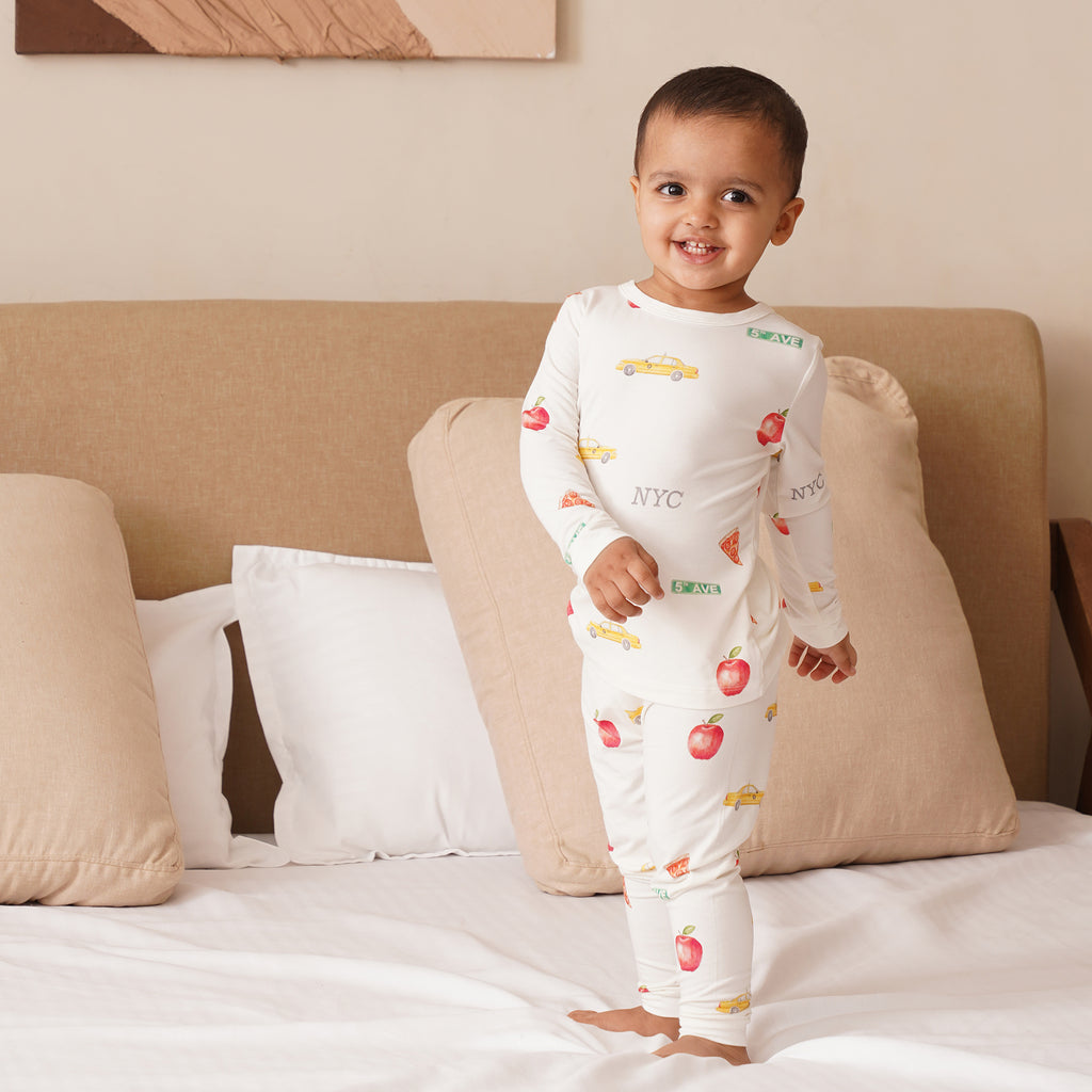 Child wearing a bamboo white onesie with colorful patterns on a bed