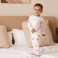 Child wearing a bamboo white onesie with colorful patterns on a bed