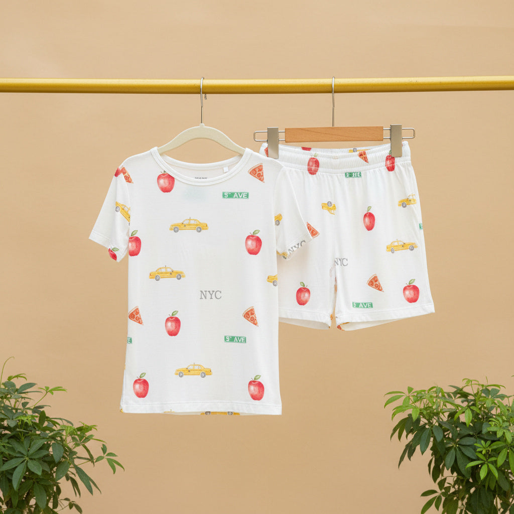 Children's pajama set with fruit and vehicle pattern on a beige background