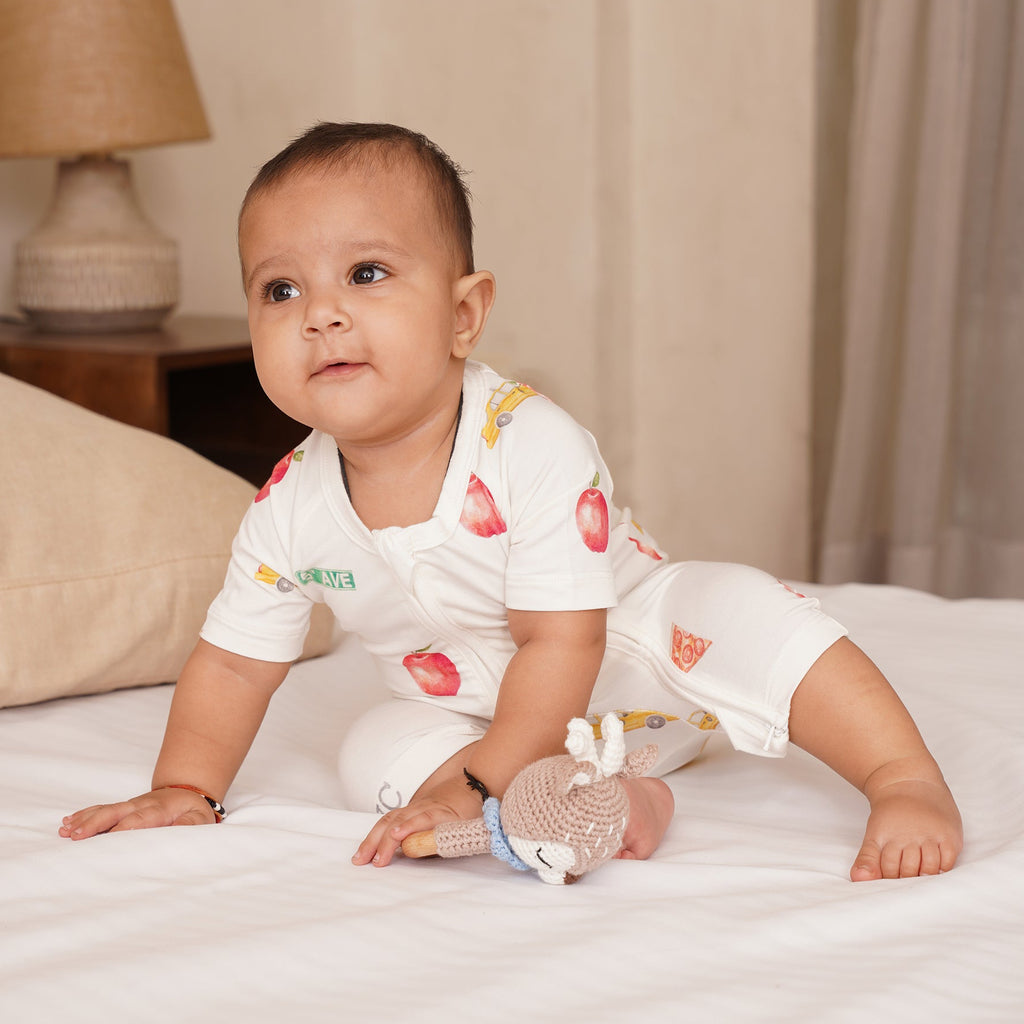 Baby in a white bamboo outfit with fruit patterns on a bed