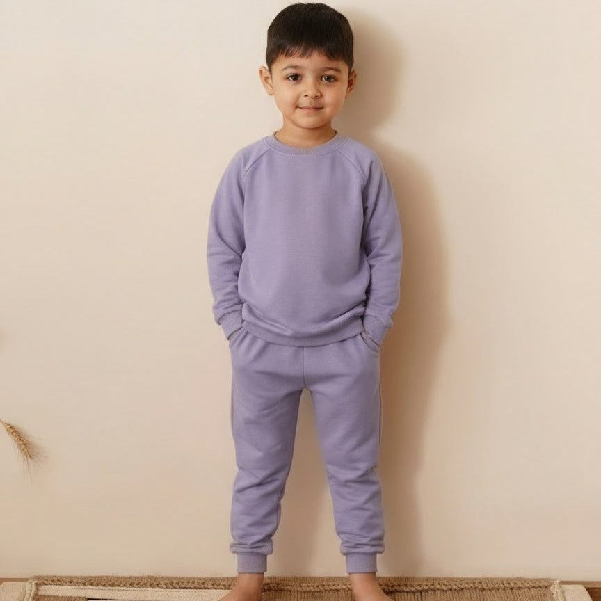 Child wearing a purple outfit standing on a mat against a plain wall