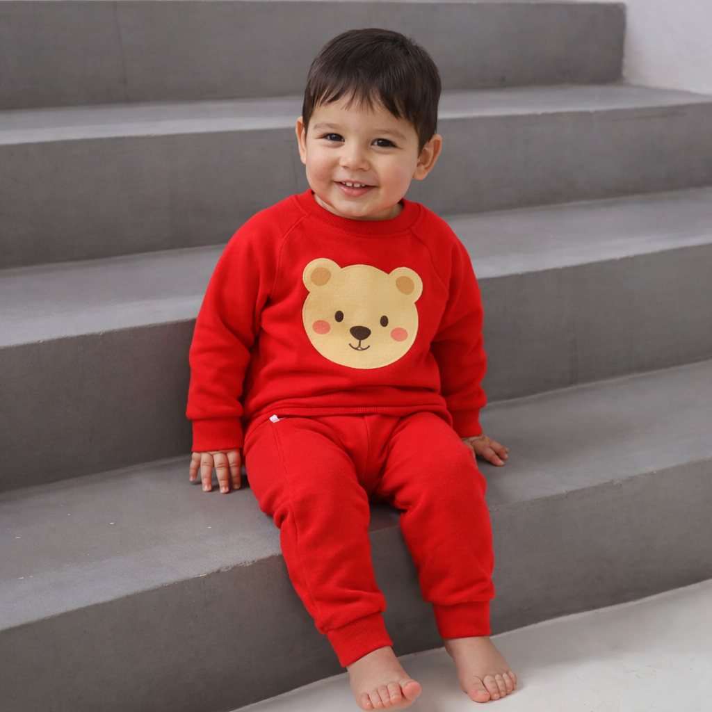 Child wearing a red outfit with a bear face design sitting on gray steps.