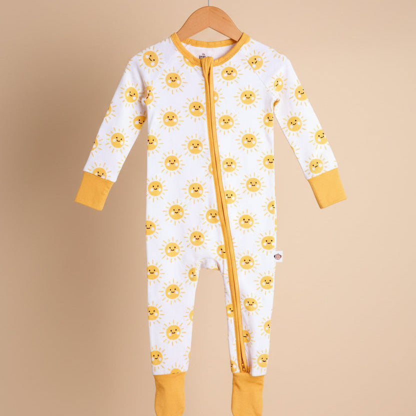 Baby onesie with yellow flower pattern on a hanger against a beige background