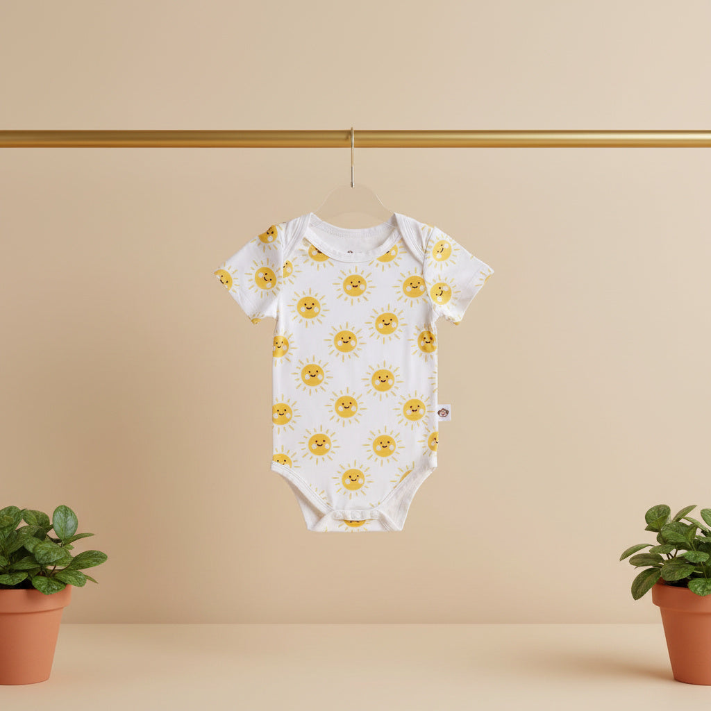 Baby onesie with yellow floral pattern hanging on a gold rod against a beige background.