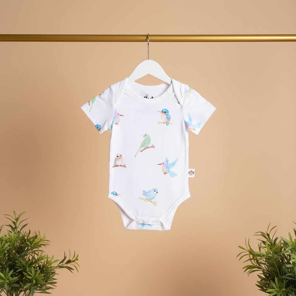 Baby onesie with bird pattern on a hanger against a beige background