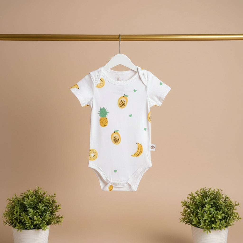 Baby onesie with fruit patterns hanging on a hanger against a beige background.
