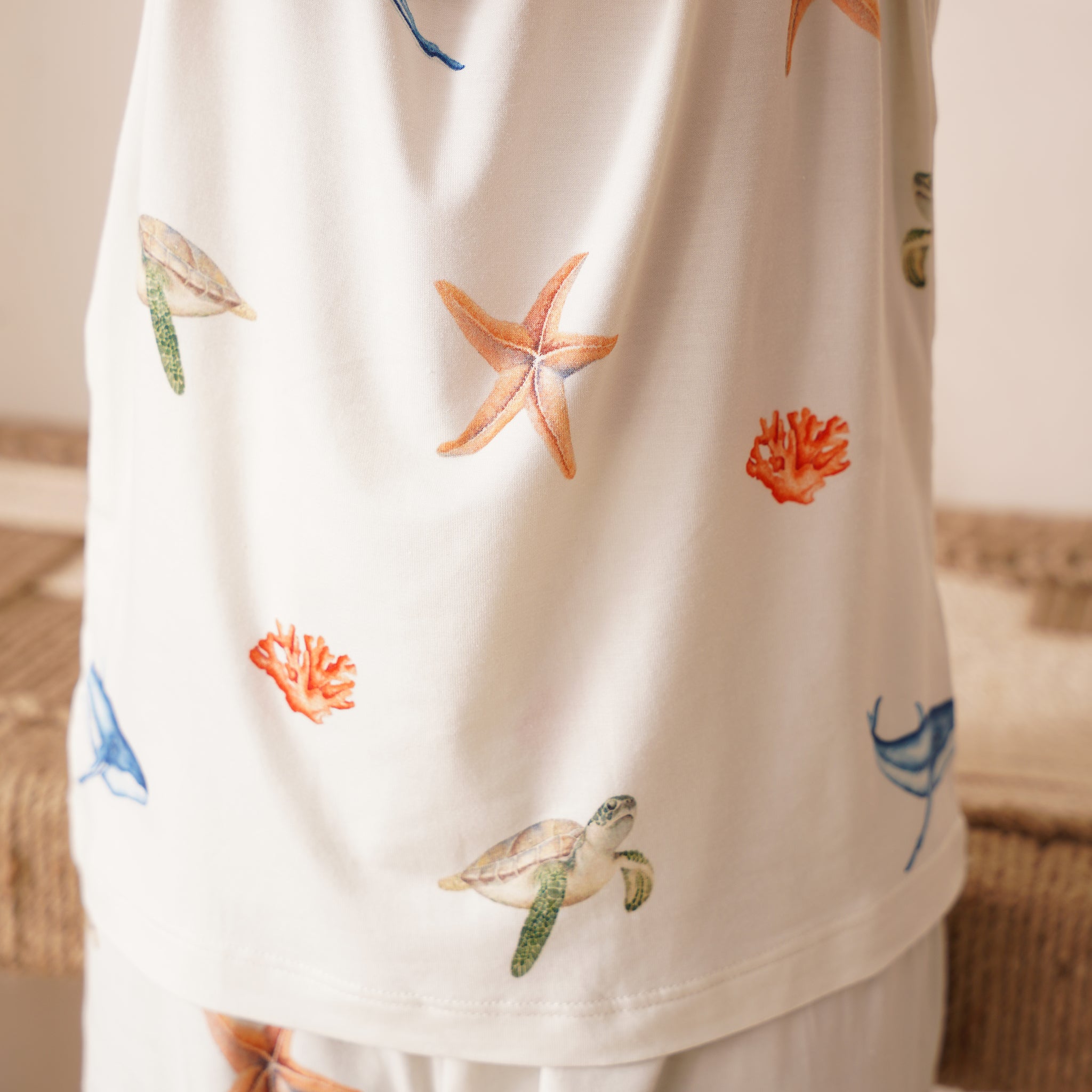 White shirt with colorful sea-themed patterns on a neutral background