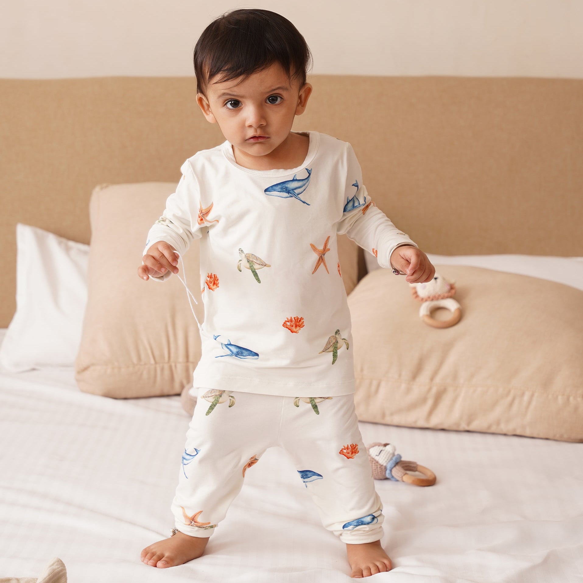 Baby wearing bamboo pajamas with animal prints on a bed