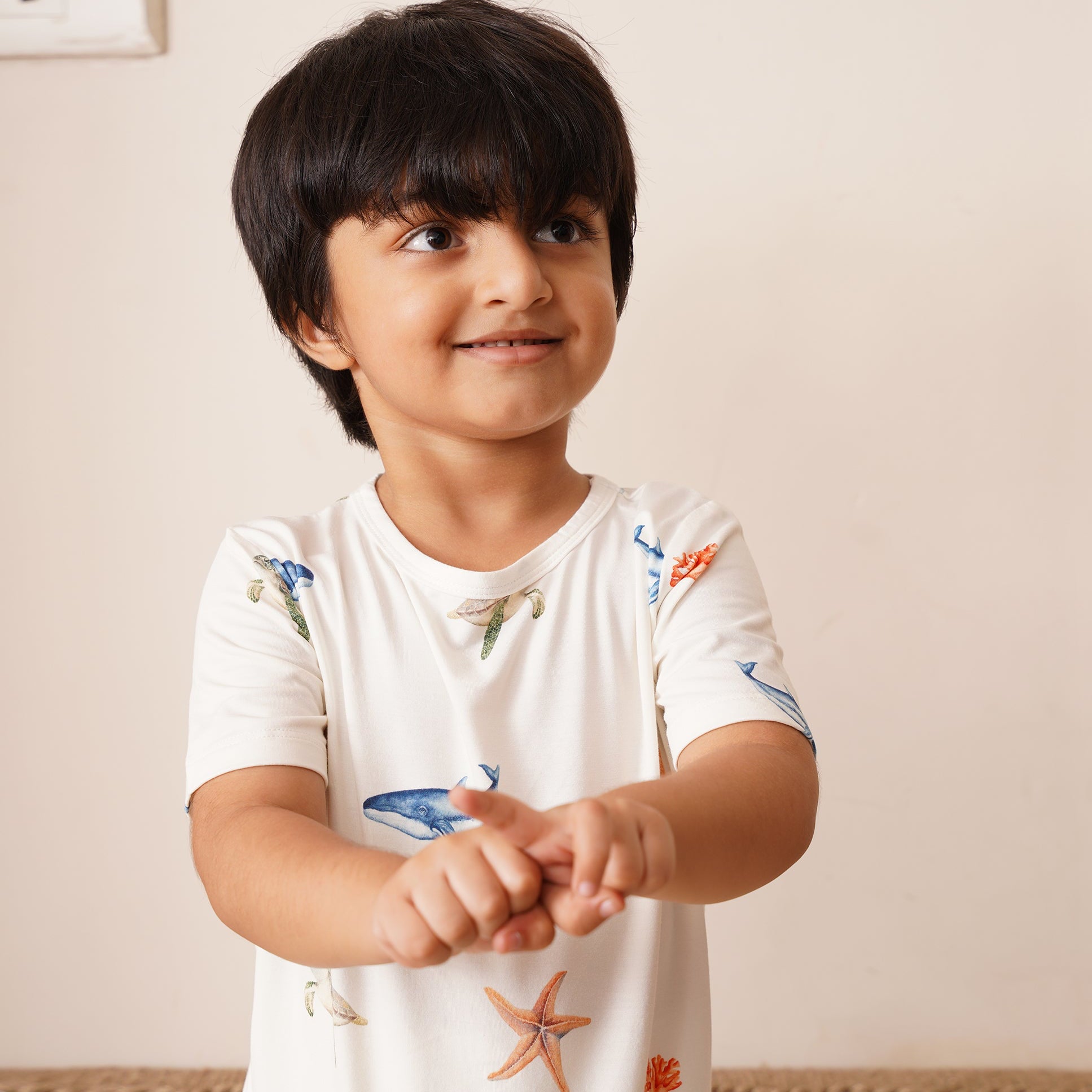 Child wearing a white bamboo shirt with colorful designs on a plain background