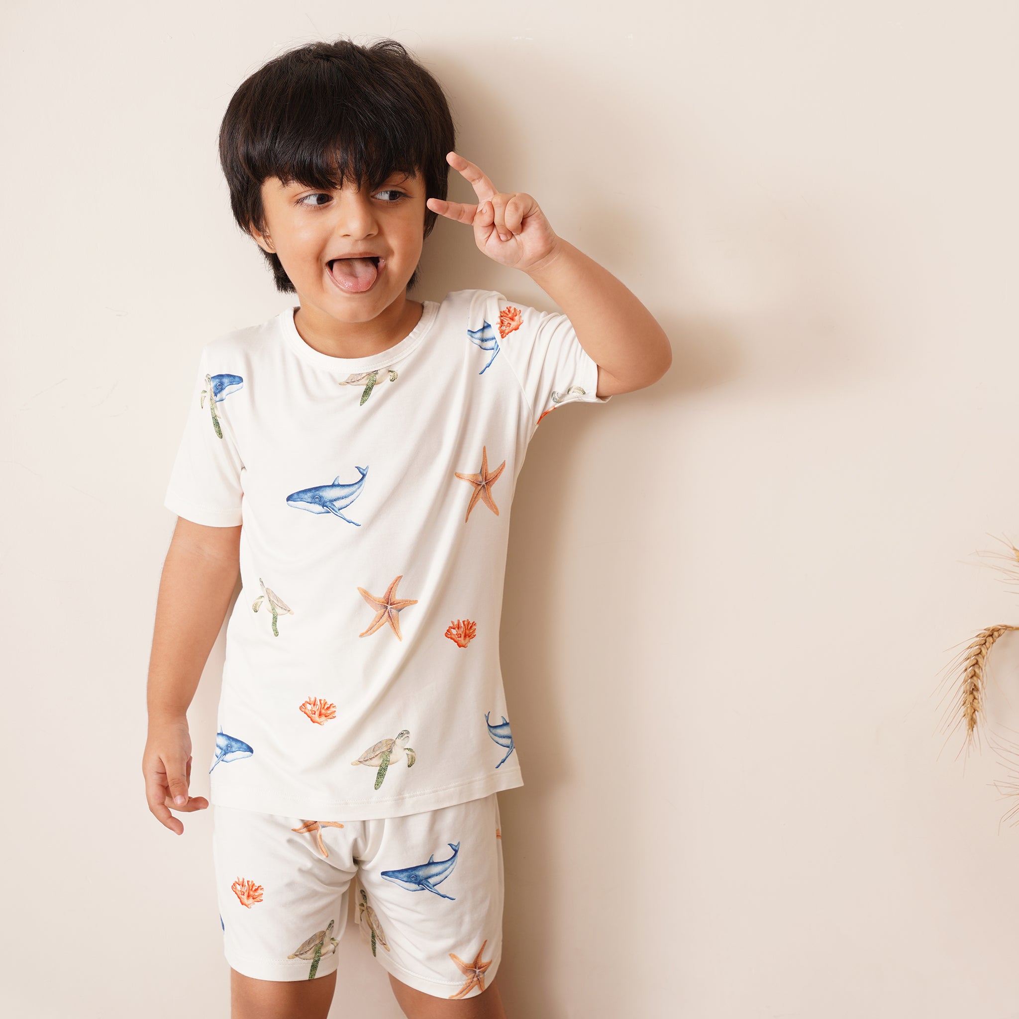 Child wearing a white bamboo outfit with sea-themed patterns on a plain background