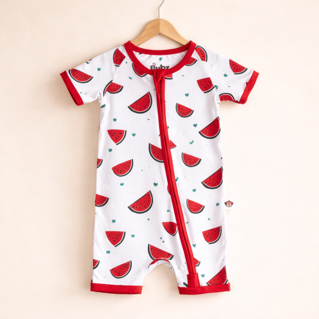 Baby romper with watermelon pattern on a hanger against a beige background