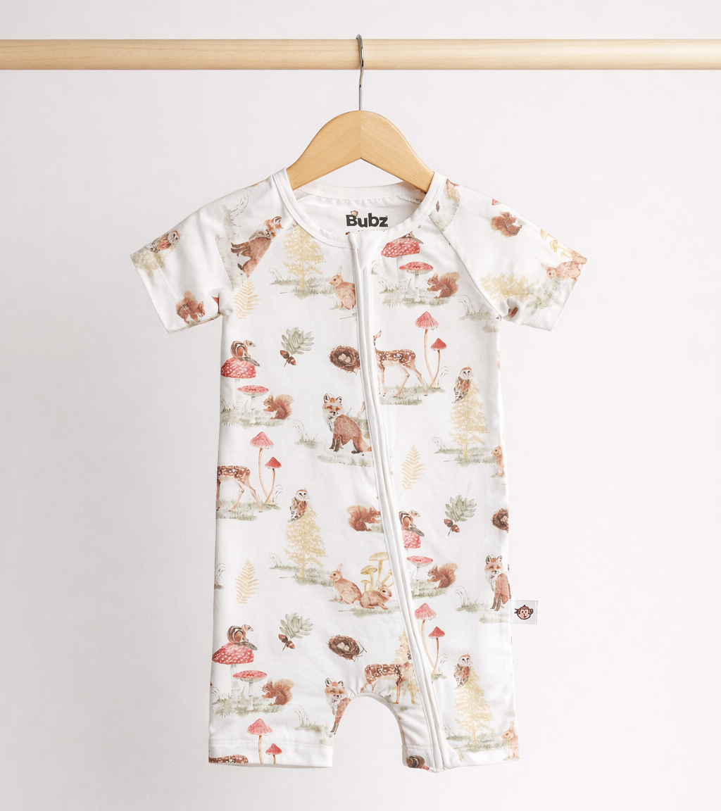 Baby romper with animal print on a wooden hanger against a white background
